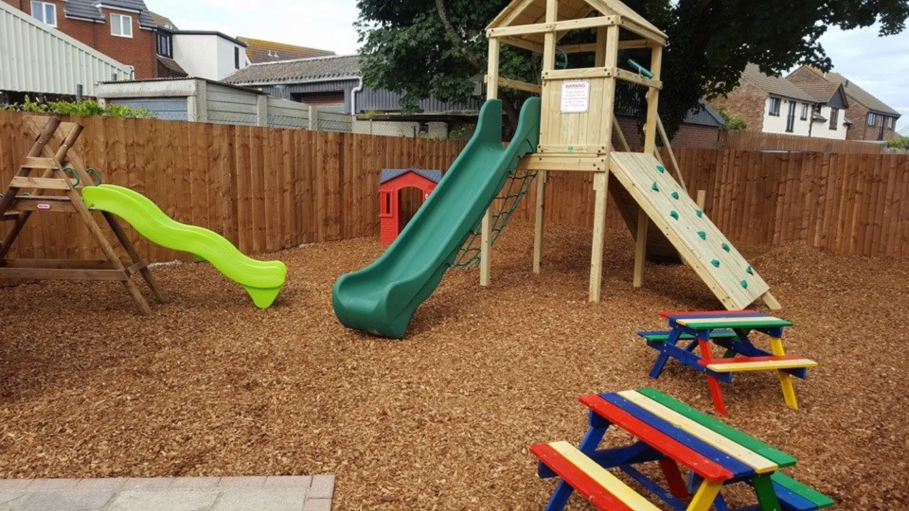 The kids play area at The Crown Inn Selsey, with slide, climbing frame and colourful picnic benches