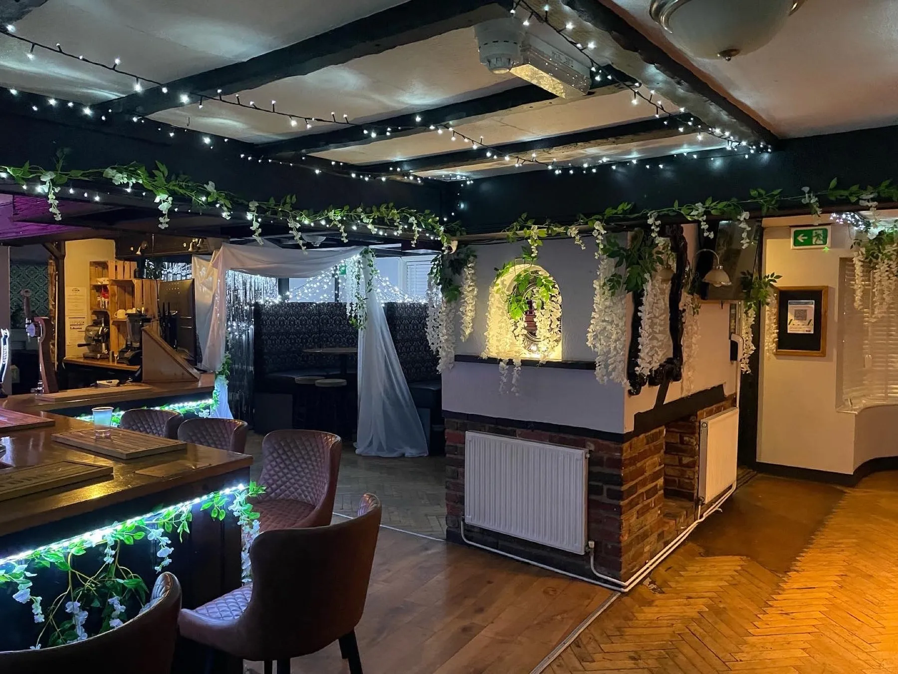 Cosy booth seating under fairy lights and trailing flowers at The Crown Inn Selsey